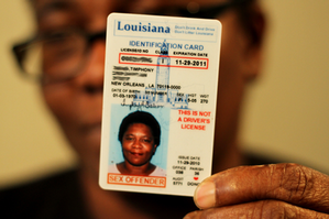 A picture of a woman holding up her drivers license that says sex offender on it.